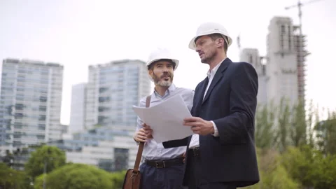 Mid-shot side view of two male engineers wearing hardhats sharing ideas while Stock Footage 277974787