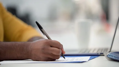 Mid-shot side view of unidentified person's hand filling out a paper form with a Stock Footage 277954451