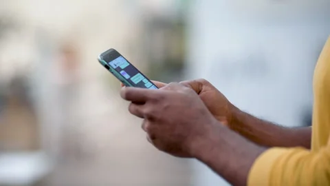Mid-shot side view of unrecognizable person's hands tapping on mobile phone Stock Footage 277954272