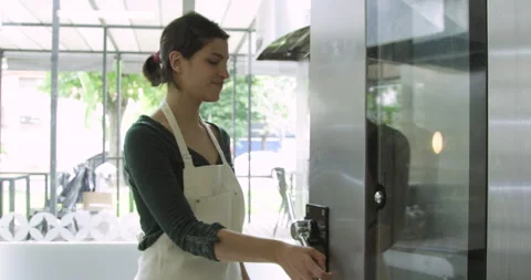 Mid-shot side view of young female entrepreneur checking progress of bread in Stock Footage 277958909