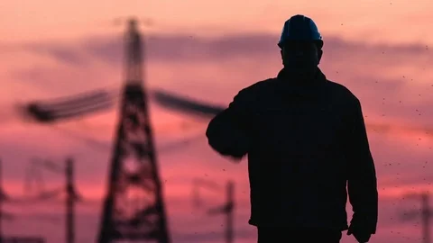 Mid shot of supervisor silhouette in hard hat going along the power lines at red Stock Footage 75636260