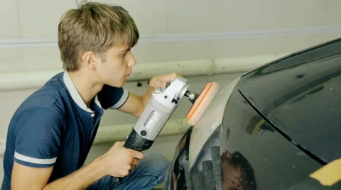 Mid shot worker polish car headlight with special tools Stock Footage 65758427