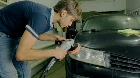 Mid shot worker polish car headlight with special tools Stock Footage 65758568