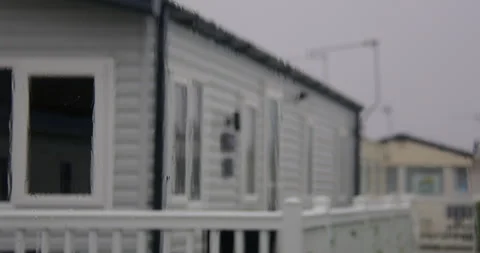 Mid zoom Shot of rain on a static caravan window with static caravans in Stock Footage 346814824