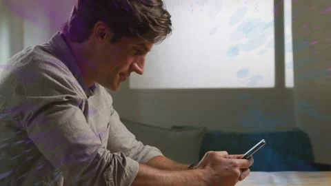 Midadult man sitting at table tapping smartphone, showing tech effect, Stock Footage 333602406