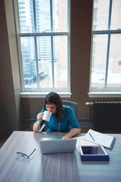 Midday coffee break to keep her refreshed. a businesswoman using a laptop during Stock Photos