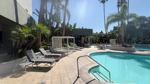 Midday Resort Swimming Pool with Empty Loungers and Cabanas Stock Footage 345369881