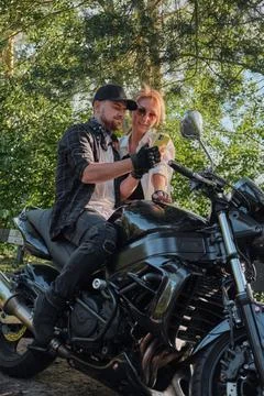 Middle age couple using mobile phone, sitting on a motorcycle, traveling Stock-Fotos