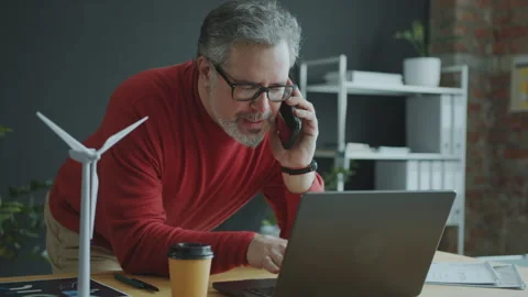 Middle Age Engineer Typing on Laptop and Speaking on Phone in Office Stock Footage 270564847