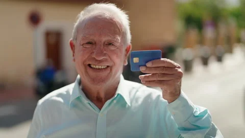 Middle age grey-haired man smiling confident holding credit card at street Stock Footage 221691627