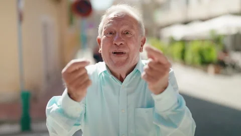 Middle age grey-haired man smiling confident doing money gesture at street Stock Footage 225061937