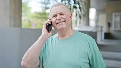 Middle age grey-haired man smiling confident talking on the smartphone at s.. Video stock 247385060