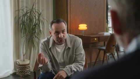 Middle age grey haired man with beard sits in psychologist office Stock Footage 273294000