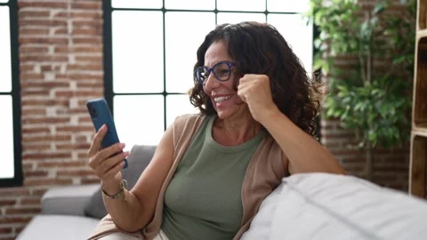 Middle age hispanic woman using smartphone and celebrating Video stock 162878504