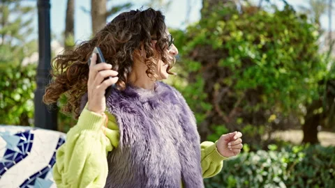 Middle age hispanic woman using smartphone dancing at park Stock Footage 242345819