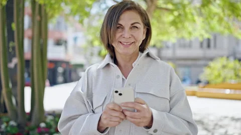 Middle age hispanic woman using smartphone at park Stock Footage 243499243