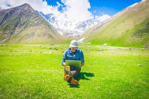 Middle age male person with white full cap sits with crossed legs on the gras Stock Photos