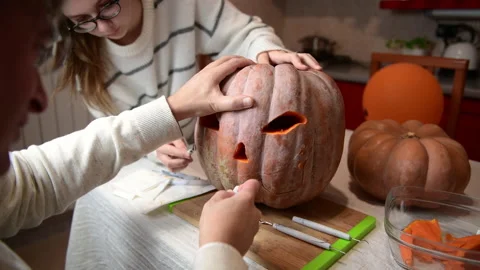 Middle age man and young woman carving pumpkin, Jack o lanterns on Halloween Stock Footage 160933642