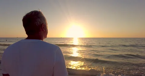 Middle age man by beach with sand looking at golden sunset. Summer vacation Stock Footage 218564183