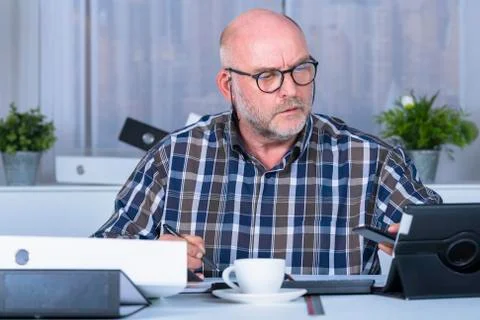 Middle age man checking his phone at his home office Stock Photos