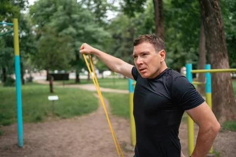 Middle age man doing strength exercises with resistance bands outdoors in park Stock Photos