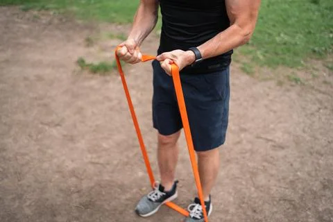 Middle age man doing strength exercises with resistance bands outdoors in park Stock Photos