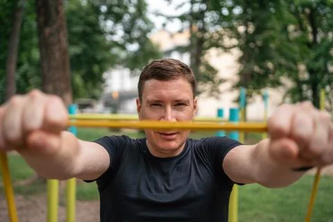 Middle age man doing strength exercises with resistance bands outdoors in park Stock Photos