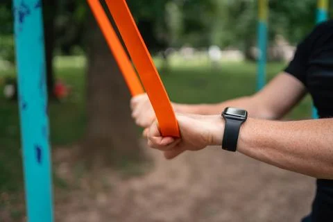 Middle age man doing strength exercises with resistance bands outdoors in park Stock Photos