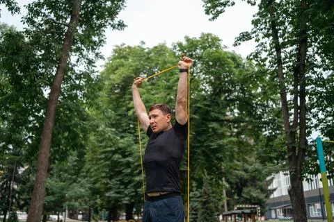 Middle age man doing strength exercises with resistance bands outdoors in park Stock Photos