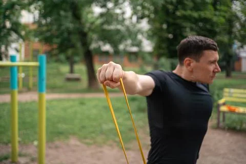 Middle age man doing strength exercises with resistance bands outdoors in park Stock Photos