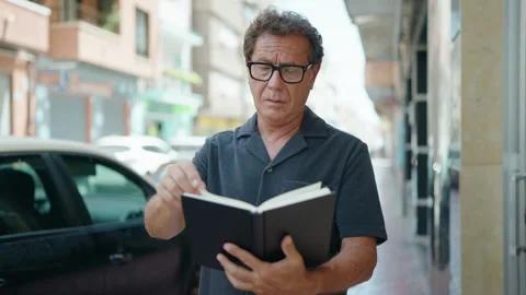 Middle age man reading book with relaxed expression at street Video stock 203277712