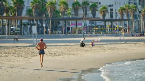 Middle age man running or jogging on sandy beach in early morning in Tel Aviv Stock Footage 312447159