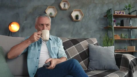 Middle age man sit couch chill see comedy drink latte in modern living room Video stock 166624197