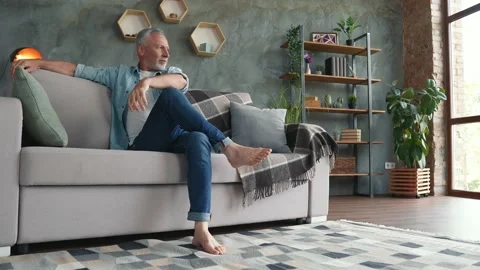Middle age man sit divan imagine like vacation in rent house Stock Footage 166623850