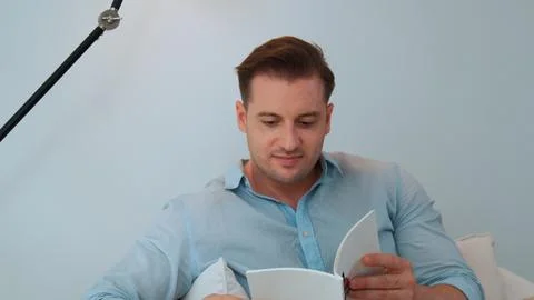 Middle age man sit on sofa read fable book increasing imagination. Divergence. Stock Photos