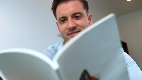 Middle age man sit on sofa read fable book increasing imagination. Divergence. Stock Photos