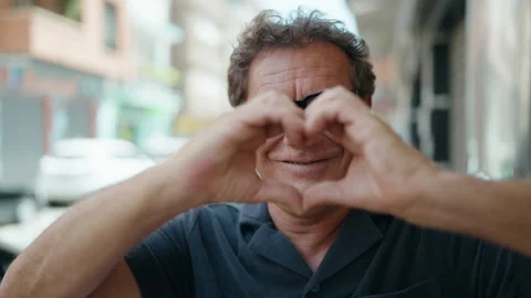 Middle age man smiling confident doing heart gesture with hands at street Stock Footage 199768919