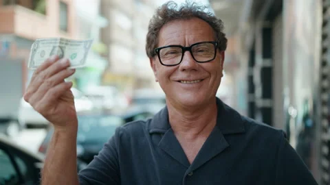 Middle age man smiling confident holding dollar at street Stock Footage 206665080