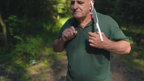 Middle Age Man trying to put on a face mask. The mask is defective. Stock Footage 157072481
