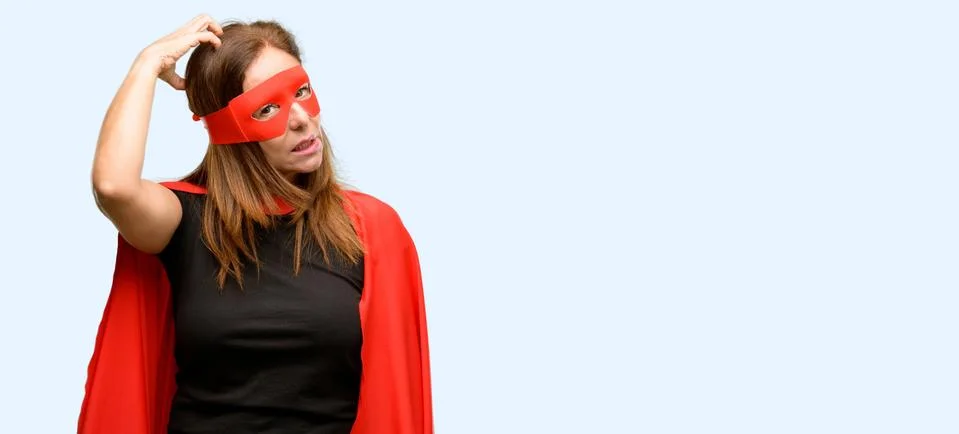 Middle age super hero woman wearing red mask and cape doubt expression, confu Stock Photos