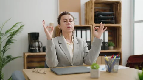 Middle age woman business worker relaxing doing yoga exercise at office Stock Footage