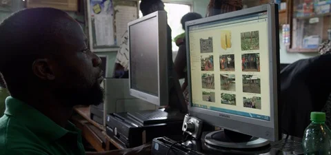Middle aged African man looking at photo images on a desktop computer Stock Footage 112142287
