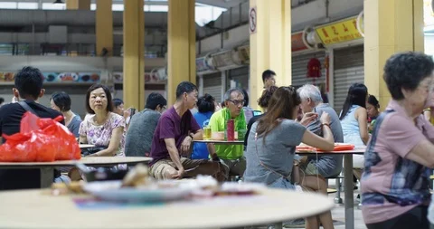 Middle-aged Asian group sitting around at a crowded hawker cent Video stock 127161499