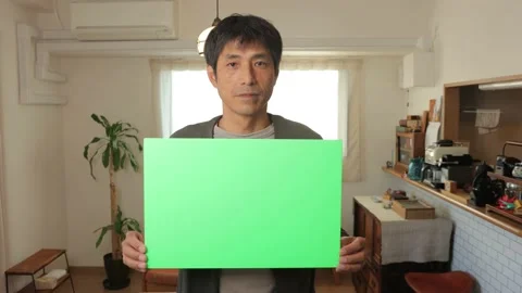 Middle aged asian man holding a green chroma board. Serious face. 25P. Stock Footage 224900062
