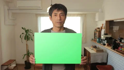 Middle aged asian man holding a green chroma board. Serious face. Stock Footage 224904602