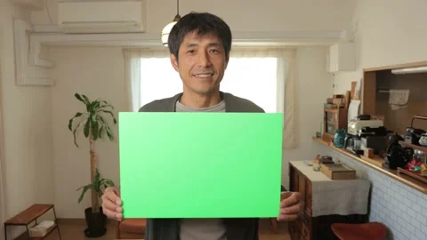 Middle aged asian man holding green board and smiles. For chromakey edit. Stock Footage 224904653