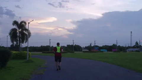 Middle-aged Asian man jogging safely at twilight with reflective gear and L.. Stock Footage 335759581