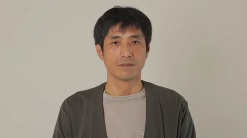 Middle aged asian man opens his eyes and stares the camera. Emotionless. Stock Footage 224903707