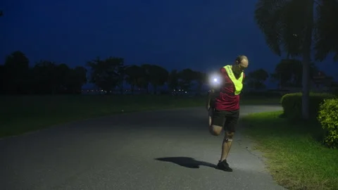 Middle-aged Asian man stretching quadriceps muscles after jogging at night Stock Footage 335759884