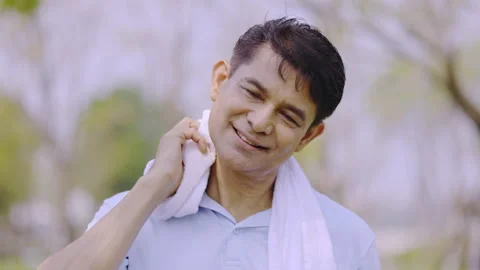 Middle-aged Asian man uses towel to wipe away sweat on face after exercising  Stock Footage 171336046